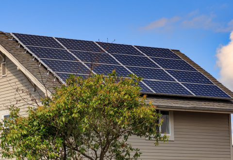A home with rooftop solar panels against a blue sky